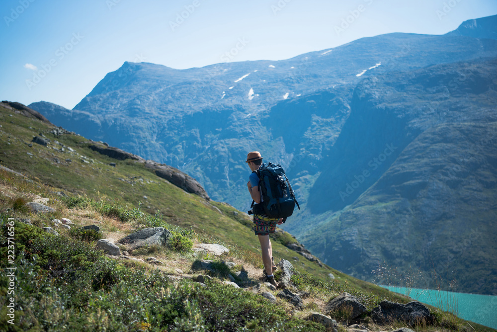 male hiker with backpack walking on Besseggen ridge over Gjende lake in Jotunheimen National Park, Norway