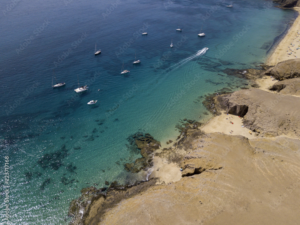 Obraz premium Vista aerea delle coste frastagliate e delle spiagge di Lanzarote, Spagna, Canarie. Strade e sentieri sterrati. Bagnanti in spiaggia e nell’Oceano Atlantico. Papagayo