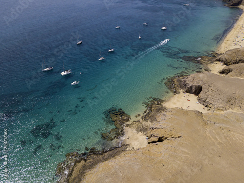 Vista aerea delle coste frastagliate e delle spiagge di Lanzarote, Spagna, Canarie. Strade e sentieri sterrati. Bagnanti in spiaggia e nell’Oceano Atlantico. Papagayo