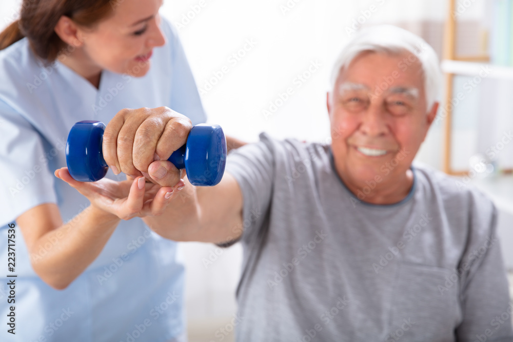 Nurse Helping Senior Man With Dumbbell Exercise Nurse Helping Senior Man With Dumbbell Exercise