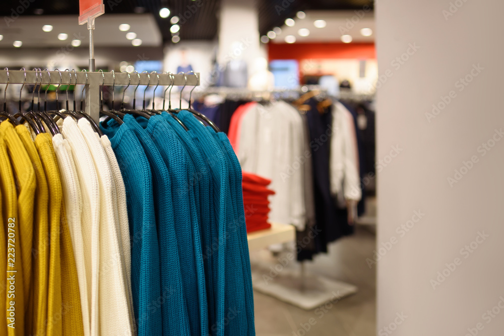 Shop women's clothing, sweaters on hangers.