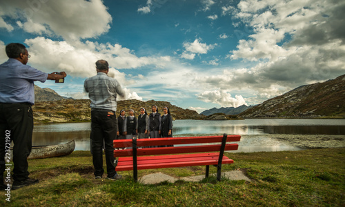 priest take a picture of nuns in a beautiful place in the alps with a lake photo