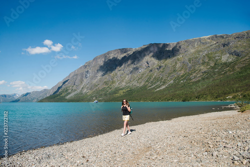 beautiful young woman with backpack walking near Gjende lake, Besseggen ridge, Jotunheimen National Park, Norway