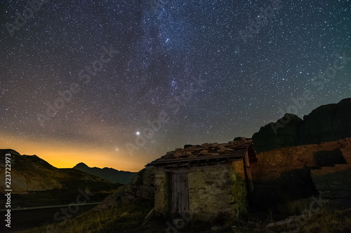 isolated house with the sky full of stars in switzerland alps