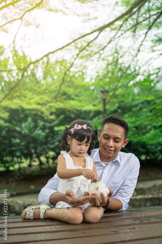 asian family teaching doughter saving on piggy bank