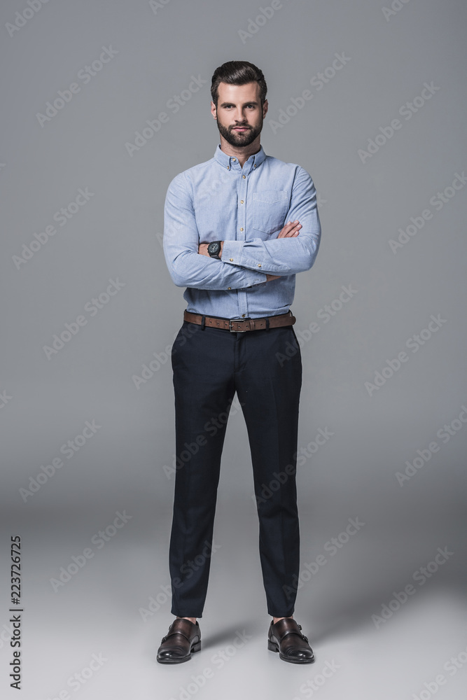 confident stylish business man posing with crossed arms, on grey confident stylish business man posing with crossed arms, on grey