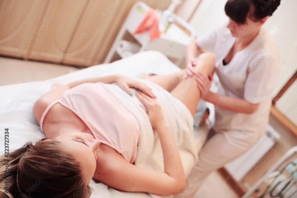 massage therapist doing a foot massage for a pregnant woman on a spa salon background massage therapist doing a foot massage for a pregnant woman on a spa salon background