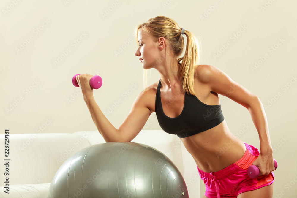 Woman with gym ball and dumbbell doing exercise Woman with gym ball and dumbbell doing exercise