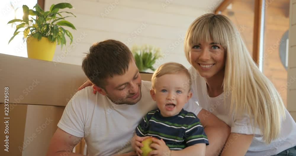 Husband and wife and playing with their son in new home. Mortgage, people, housing and real estate concept - happy family portrait moving to new house Husband and wife and playing with their son in new home. Mortgage, people, housing and real estate concept - happy family portrait moving to new house