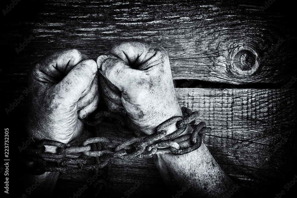 Powerful dirty male hands clenched into fists chained with rusty chain. Black and white photo. Powerful dirty male hands clenched into fists chained with rusty chain. Black and white photo.