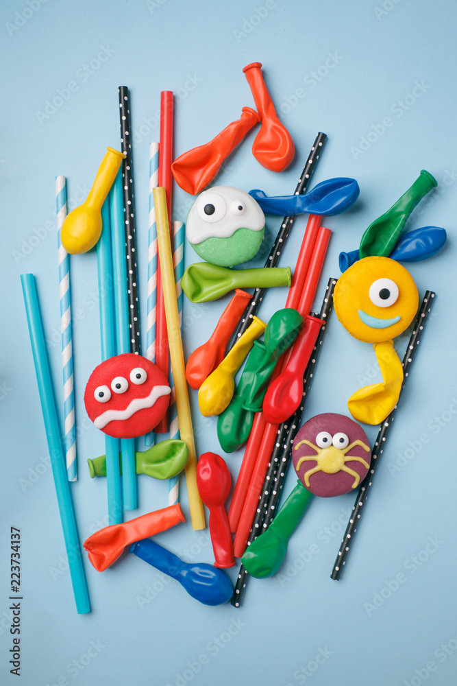Children birthday halloween party background, frame with sweets, cocktail straws and balloons on blue surface, copy space, top view Children birthday halloween party background, frame with sweets, cocktail straws and balloons on blue surface, copy space, top view