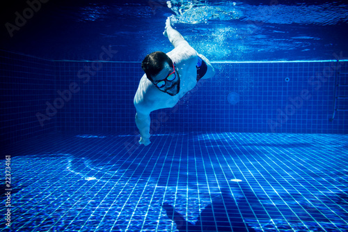 young man with sunglasses enjoying the swimming pool abstract summer fun underwater swimming jump diving background photo