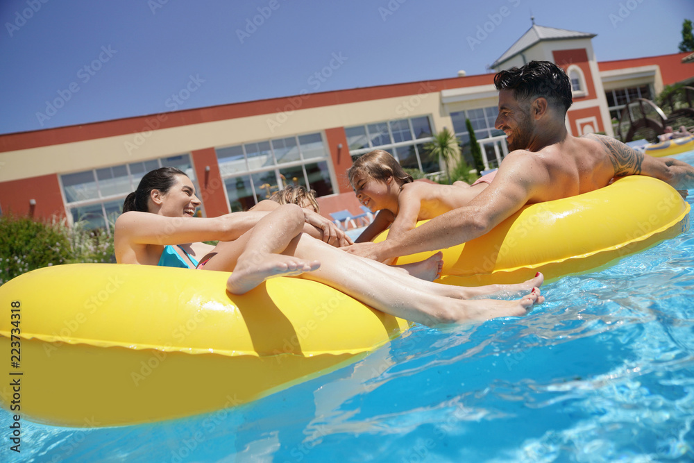 Obraz premium Family having fun riding inflatable ring at the pool