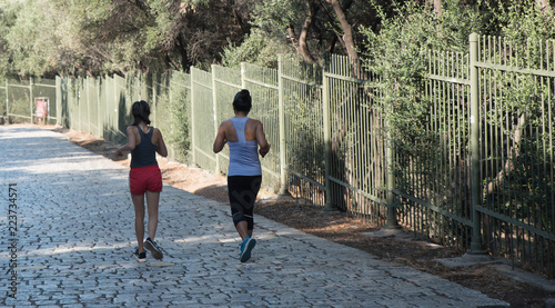 Woman and teen running on cobbleston roadl in Athens photo