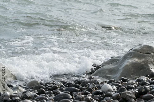 Obraz Małe fale uderzają w skały na plaży w słoneczny dzień.