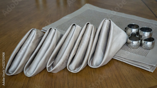 Golden fancy napkins folded in triangl, metal rings & place mats for table setting in event celebration party or holiday