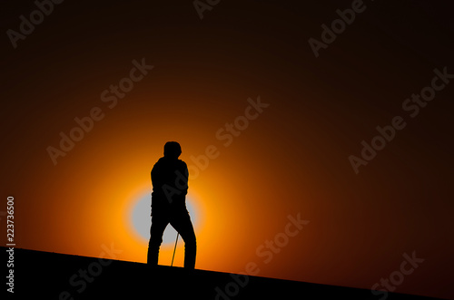 Silhouette male golfers are golfing with warm light of sunset