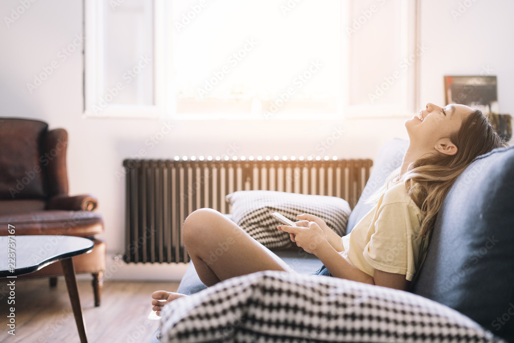 Laughing woman with phone chilling on sofa Laughing woman with phone chilling on sofa