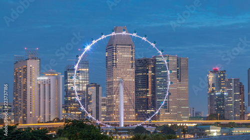 Skyline of Singapore with famous Singapore Ferries Wheel night to day timelapse