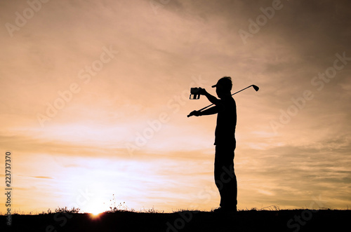 Silhouette golf athlete was photographed himself with a beautiful sky of sunset