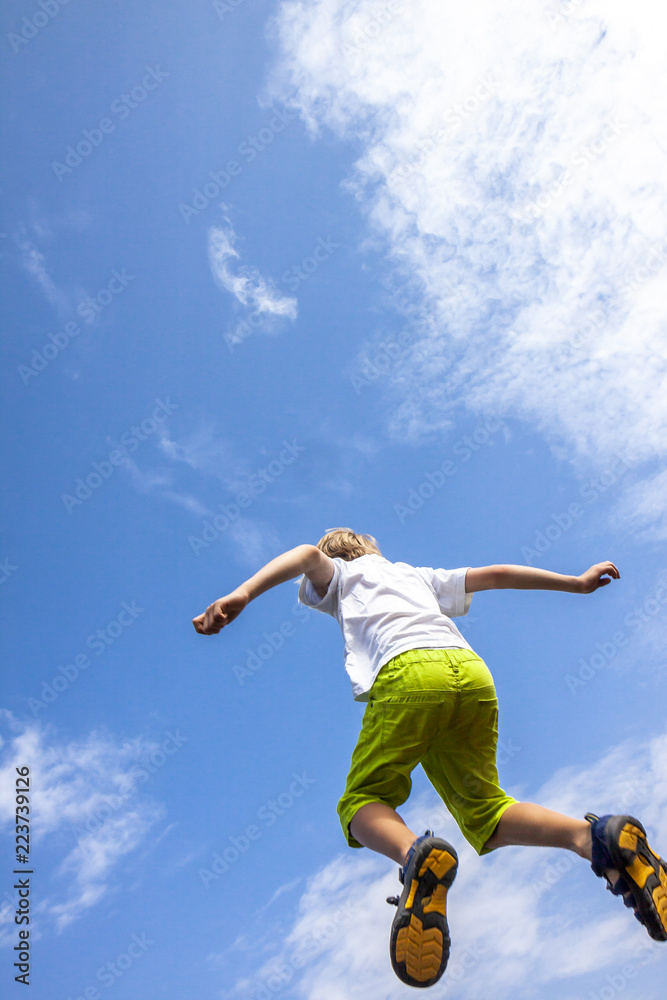 happiness, childhood, freedom, movement and people concept - happy boy jumping in air into the blue sky happiness, childhood, freedom, movement and people concept - happy boy jumping in air into the blue sky