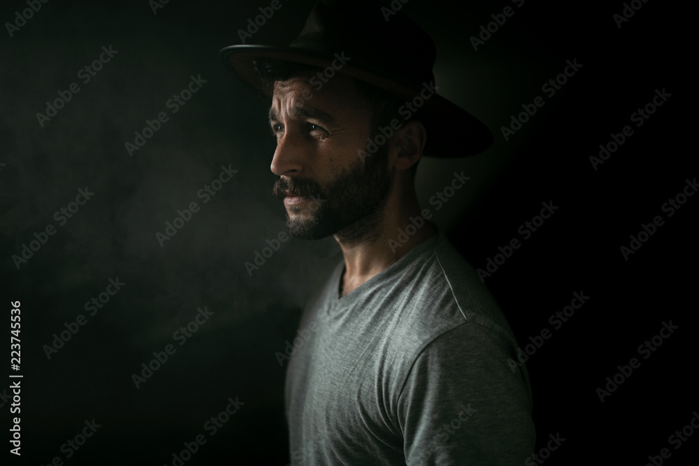 Man in hat standing against black background Man in hat standing against black background