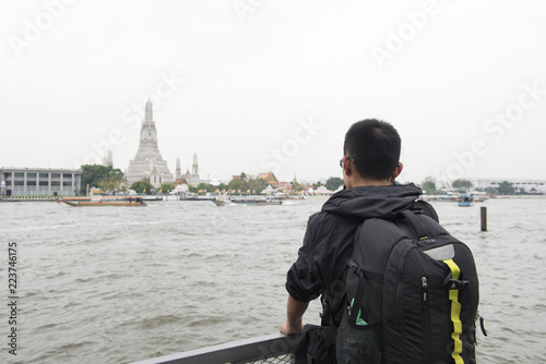 Young asian man look Bangkok temple and Chao Phra ya river.