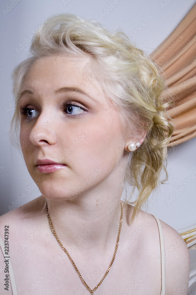 portrait of a young beautiful girl with blue eyes and blonde hair daydreaming in her boudoir