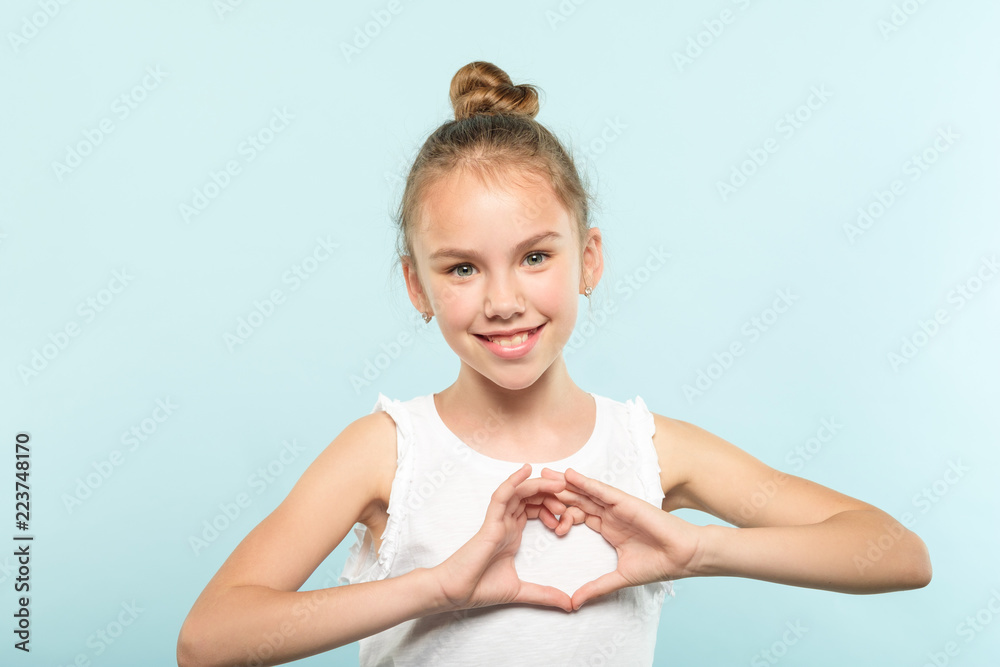 love and emotions expression. cute smiling young child making a heart shape with her hands. happy girl on blue background. love and emotions expression. cute smiling young child making a heart shape with her hands. happy girl on blue background.