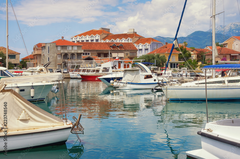 Beautiful Mediterranean landscape.  Seaside town: houses with red roofs and fishing boats in harbor. Montenegro, Tivat city, view of Marina Kalimanj