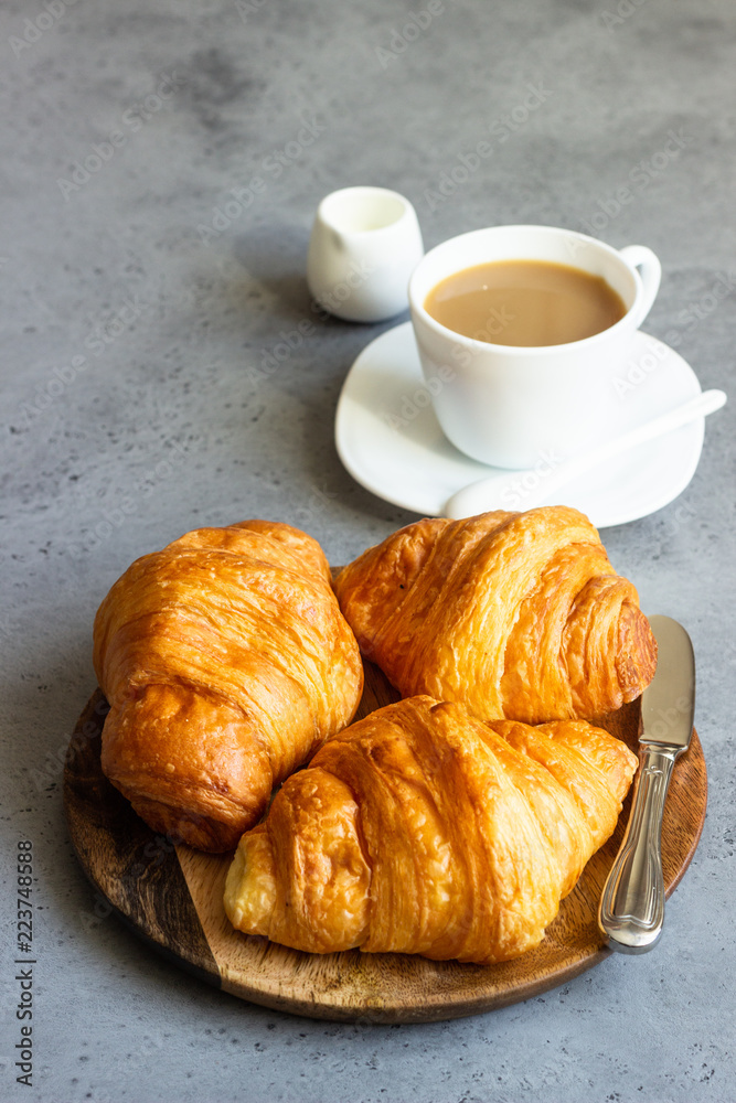 Fresh butter croissants on wooden plate on grey concrete background. Fresh butter croissants on wooden plate on grey concrete background.