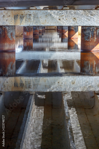 The abstract background with the lower part of the concrete bridge and its reflection in the water surface