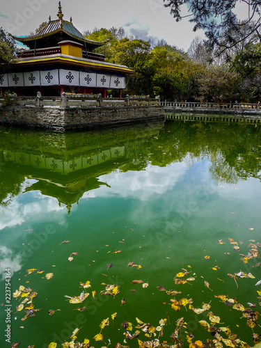 Pagoda and green reflecting pond with floating yellow leaves at Norbulingka, the Dalai Lama's summer palace in Lhasa, Tibet photo