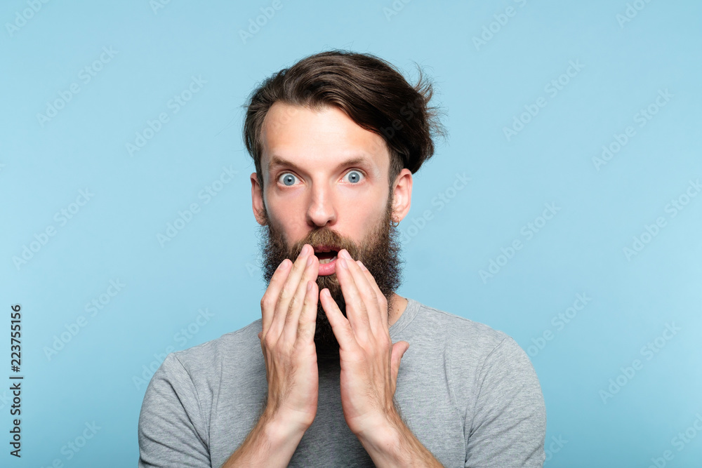 omg unbelievable shock amazement. astounded man with open mouth. portrait of a young bearded guy on blue background. emotion facial expression and reaction concept. omg unbelievable shock amazement. astounded man with open mouth. portrait of a young bearded guy on blue background. emotion facial expression and reaction concept.