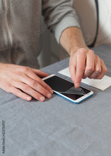 Protect repair service concept. High angle top view cropped vertical photo of repairman help, installing new glass and takes an old protective film on the phone by hands, without tools © brizmaker