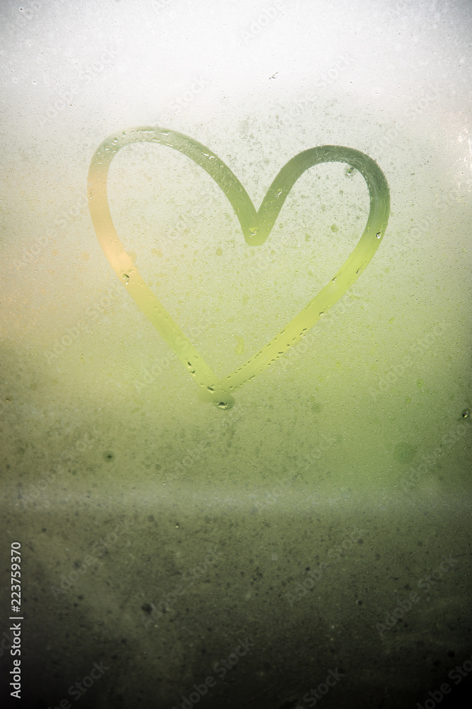 A heart painted on a misted window.Heart on misted glass. Heart on a window background.Heart symbol of love drawn on the glass.
