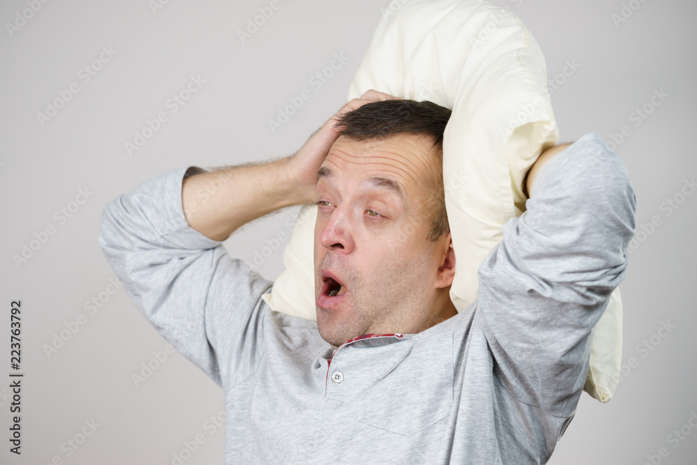Man sleepy tired with pillow yawning on grey Man sleepy tired with pillow yawning on grey