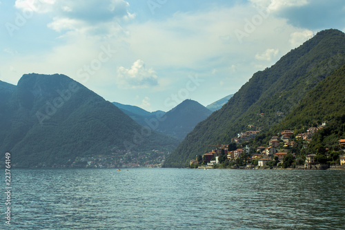 Landscape Lake Como, the silhouettes of the alpine hills above it and the cloudy sky.
