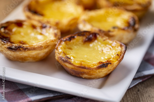 Typical Portuguese custard pies - "Pastel de Nata" or "Pastel de Belem". traditional portuguese pastry. On a wooden table. © beto_chagas