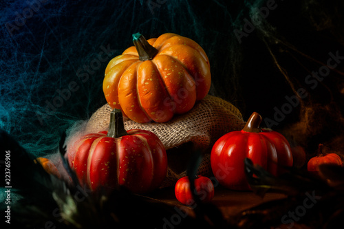 Spooky dark Halloween background with cobweb, pumpkins and spiders. Halloween party decor with blue backlit photo