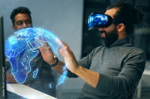 deadline, augmented reality and technology concept - creative man with virtual headset or vr glasses and earth globe hologram at night office