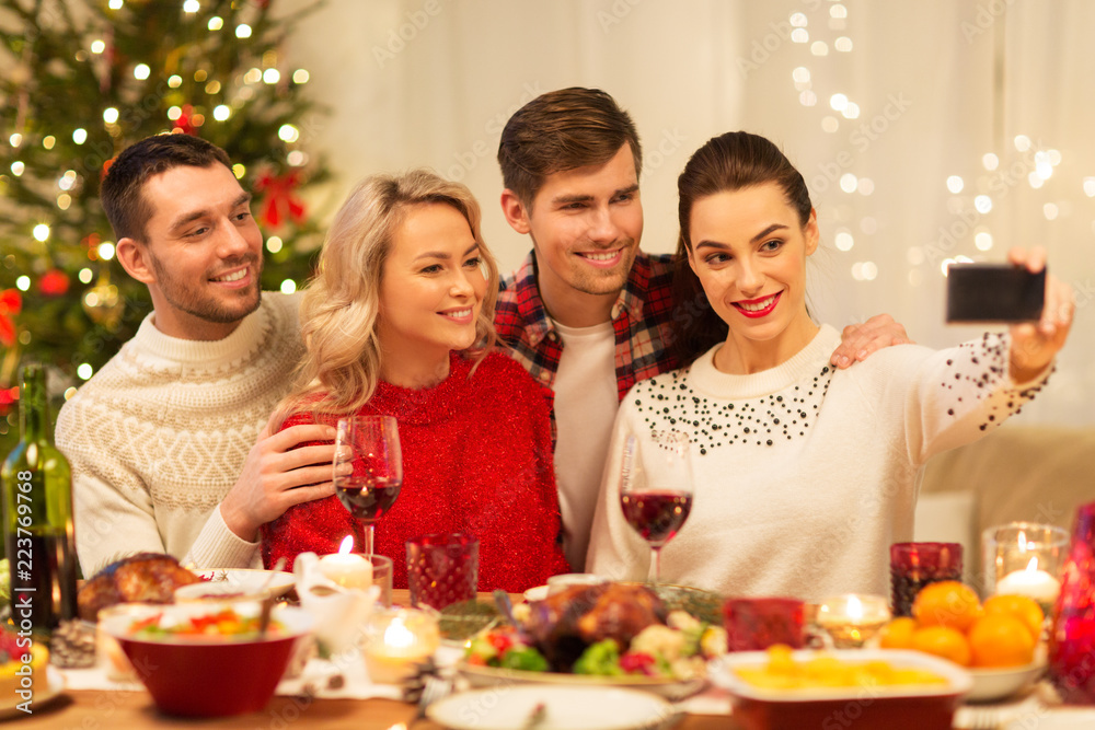 holidays and celebration concept - happy friends taking selfie by smartphone at home christmas dinner holidays and celebration concept - happy friends taking selfie by smartphone at home christmas dinner