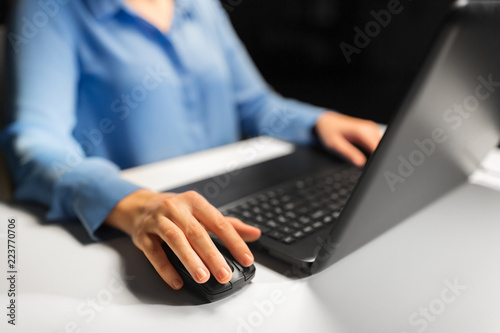 business, education, people and technology concept - close up of female hand with laptop and computer mouse on table