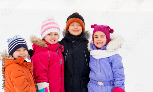 childhood, friendship and season concept - group of happy little kids in winter clothes outdoors