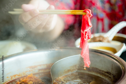 chopsticks take beef slice into shabu shabu pot,  healthy food.  image for background, wallpaper ,copy space.
