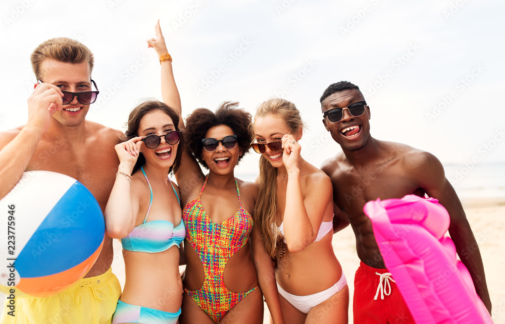 friendship, summer holidays and people concept - group of happy friends in sunglasses on beach