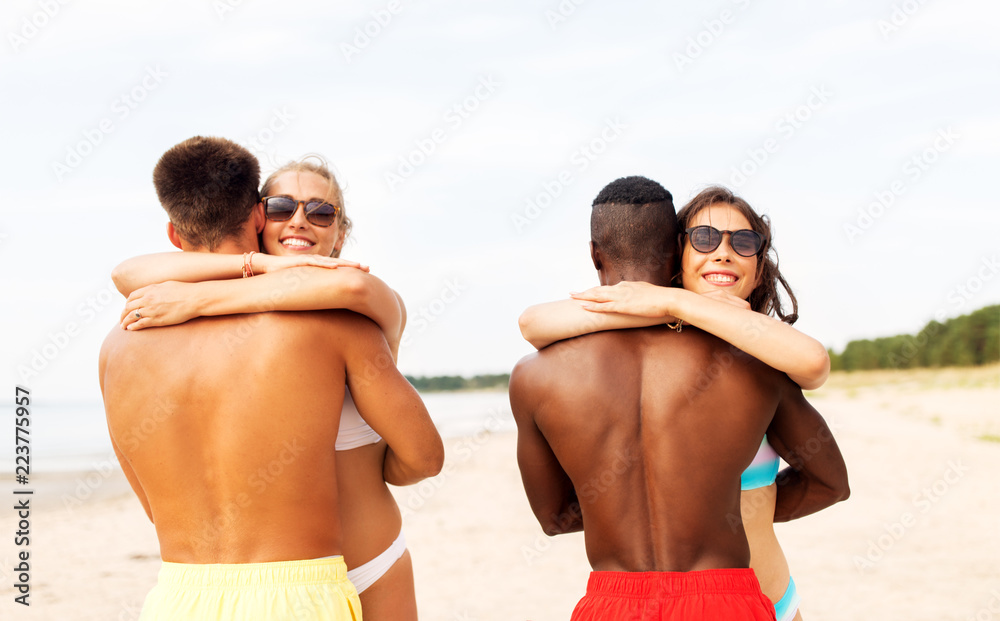 friendship, summer holidays and people concept - happy friends or couples hugging on beach friendship, summer holidays and people concept - happy friends or couples hugging on beach