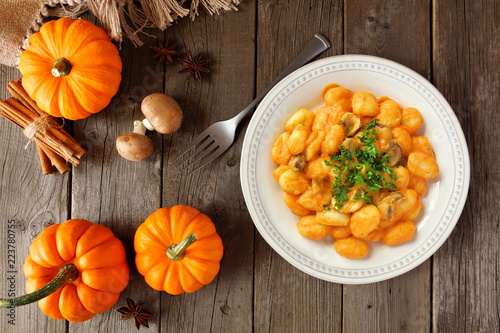 Gnocchi with a pumpkin, mushroom cream sauce. Autumn meal. Above view table scene on a wood background.