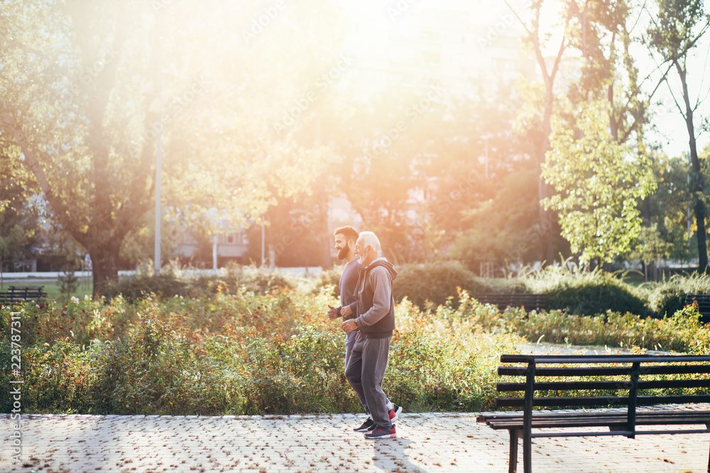 Fototapeta premium Happy father and son jogging together outdoors in park.