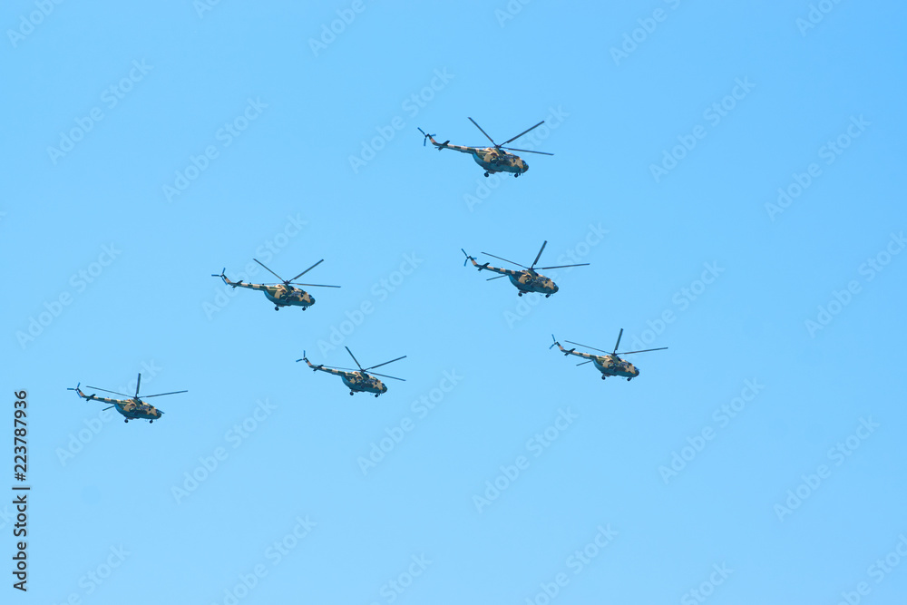 Military helicopters maneuvers in the blue sky. Group combat helicopters in flight during a military demonstration Military helicopters maneuvers in the blue sky. Group combat helicopters in flight during a military demonstration